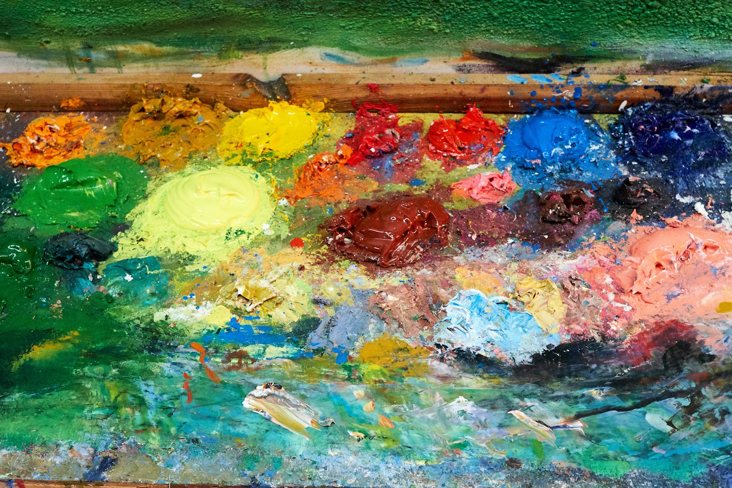 Tavolozza da pittore in legno con macchie di colori ad olio mescolati.