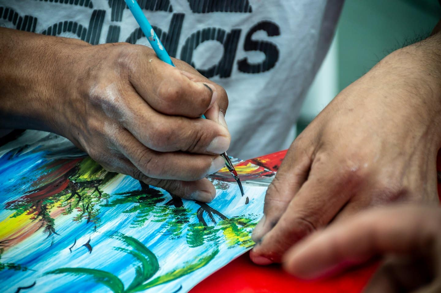Artista che dipinge un paesaggio colorato con un pennello sottile.