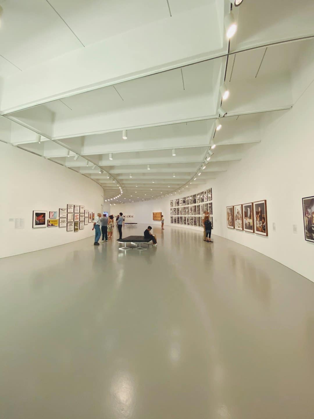 Visitatori esaminano opere d'arte in una galleria moderna e luminosa.